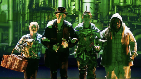 Four actors crossing arms with each other in customers and makeups on stage