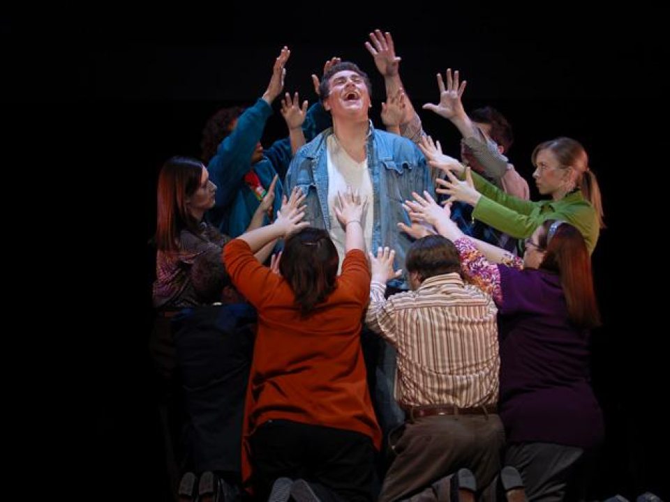 man in the center laughing when people surrounded him with their hands raised to him