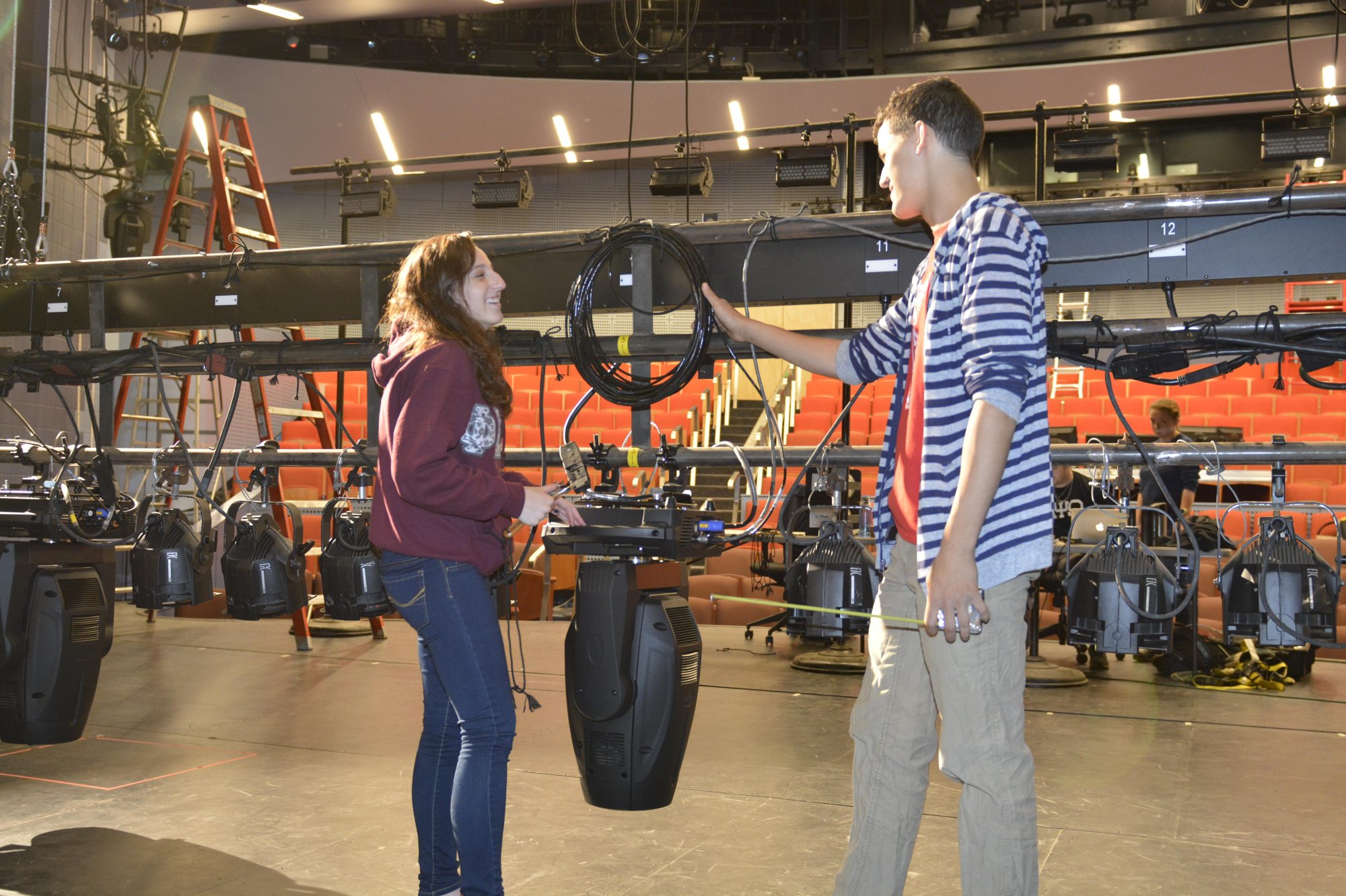 image of two students on a theatre stage working as technicians smiling and laughing at each other