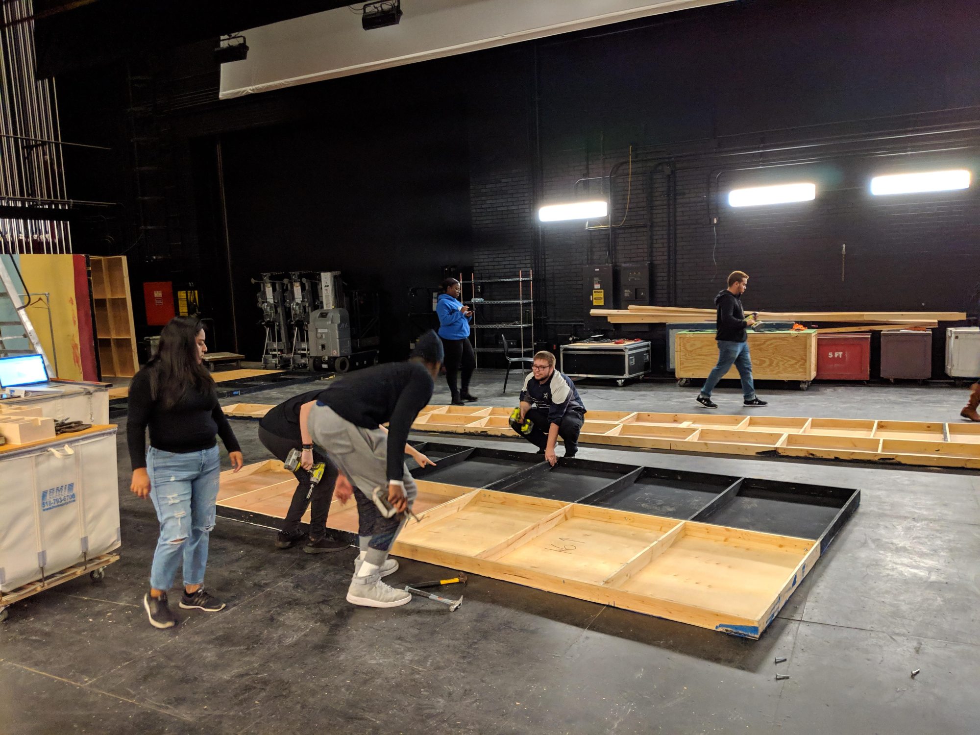 stage crew building props and smiling at each other from a distance