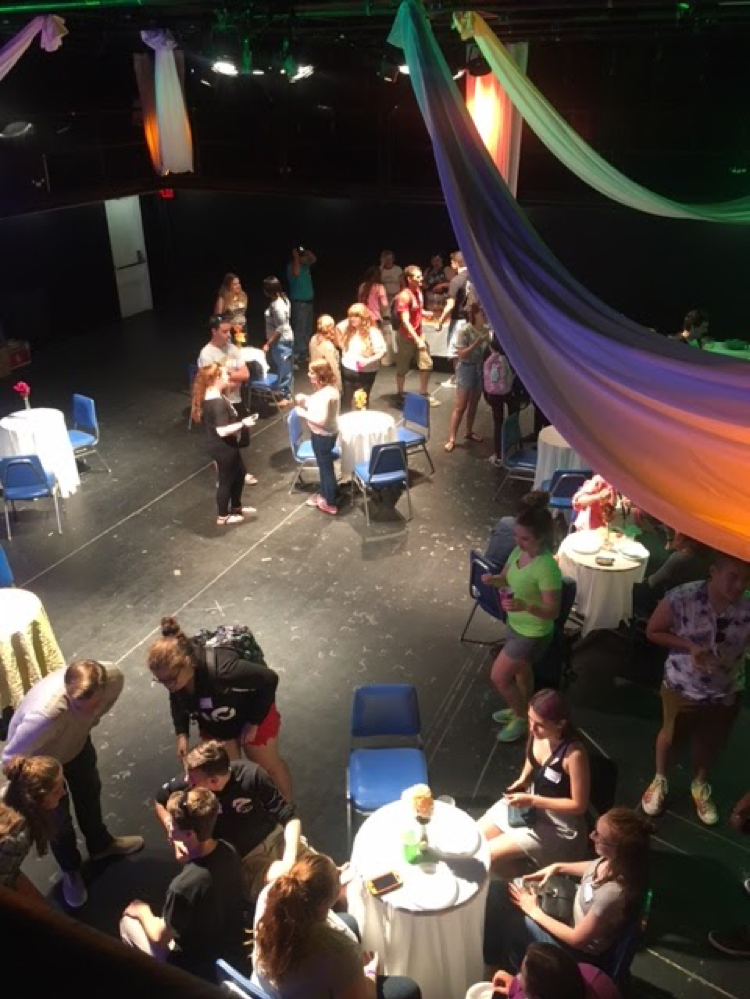 guests and students alike at a backstage tea party chatting and having fun