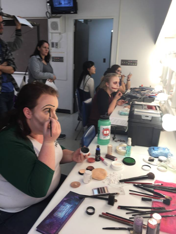 people from theatre workshops sitting in the dressing room, trying on makeup