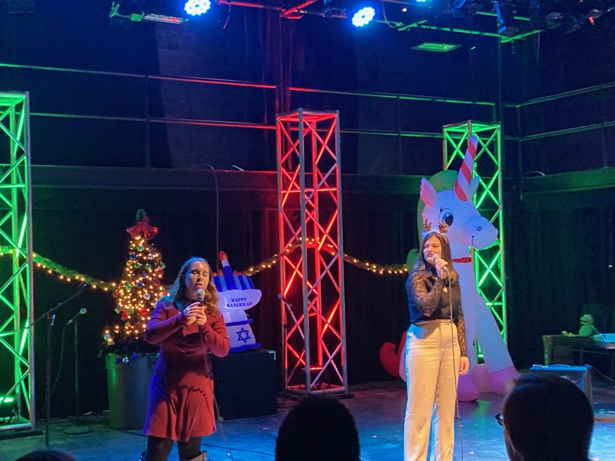 Two singers performing in front of holiday decortations