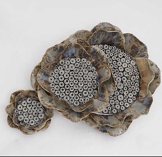 This piece is wall piece. This work of art is made up of three pieces, two which fit and overlap each other. The third piece however is not attached to the others, so it can be positioned to the individuals liking. The main focus of this piece has a very unique and abstract inside made up tiny pocked holes, while the outside is simplified so that the eye is drawn to the center of this piece.