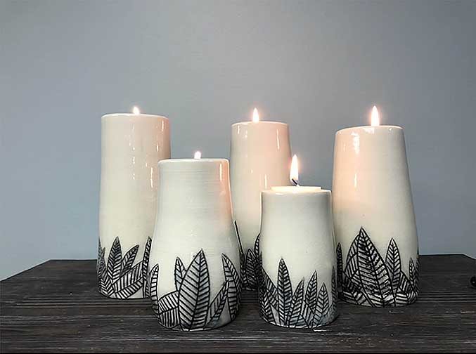 The piece is a set of five cylindrical candle holder, ranging is all sizes. These pieces are also made from porcelain clay because of the natural white clay body. On the bottom of these pieces, there are carved leaf&#039;s that were filled in with black underglaze. These candle holders have a very elegant and relaxing feel to them.