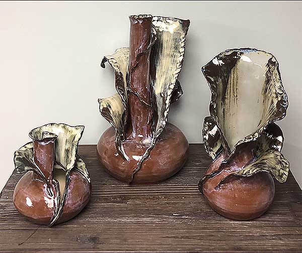 This piece is made up of three vases (one large, one medium and one small). The three vases have very different looks. The bottom of these vases are thrown and then the top is hand built. These vases come together as a set because of the glazes used.