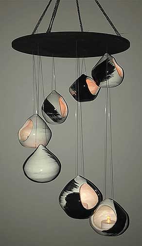 This work is made up of many small thrown pieces. These are decorated with a black and white brushed design. The small opening is made for a candle. These pieces are hung by fishing line the create the illusion of them floating and they are all hung at different lengths.