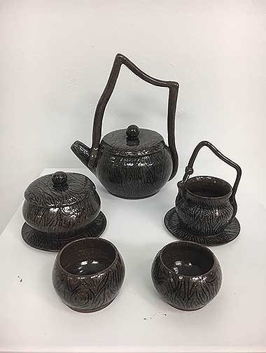 This teapot set is thrown with red clay and has hand built handles added to the pieces. These pieces have a wood grain texture carved into them. All of the pieces were just glazed in a clear glaze.
