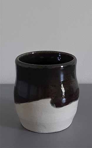 A handleless mug with a bulged midsection, the glazing application of dark green and white resulted in what can be interpreted as a wave.