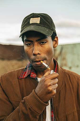 A portrait of a man lighting a cigarette. 