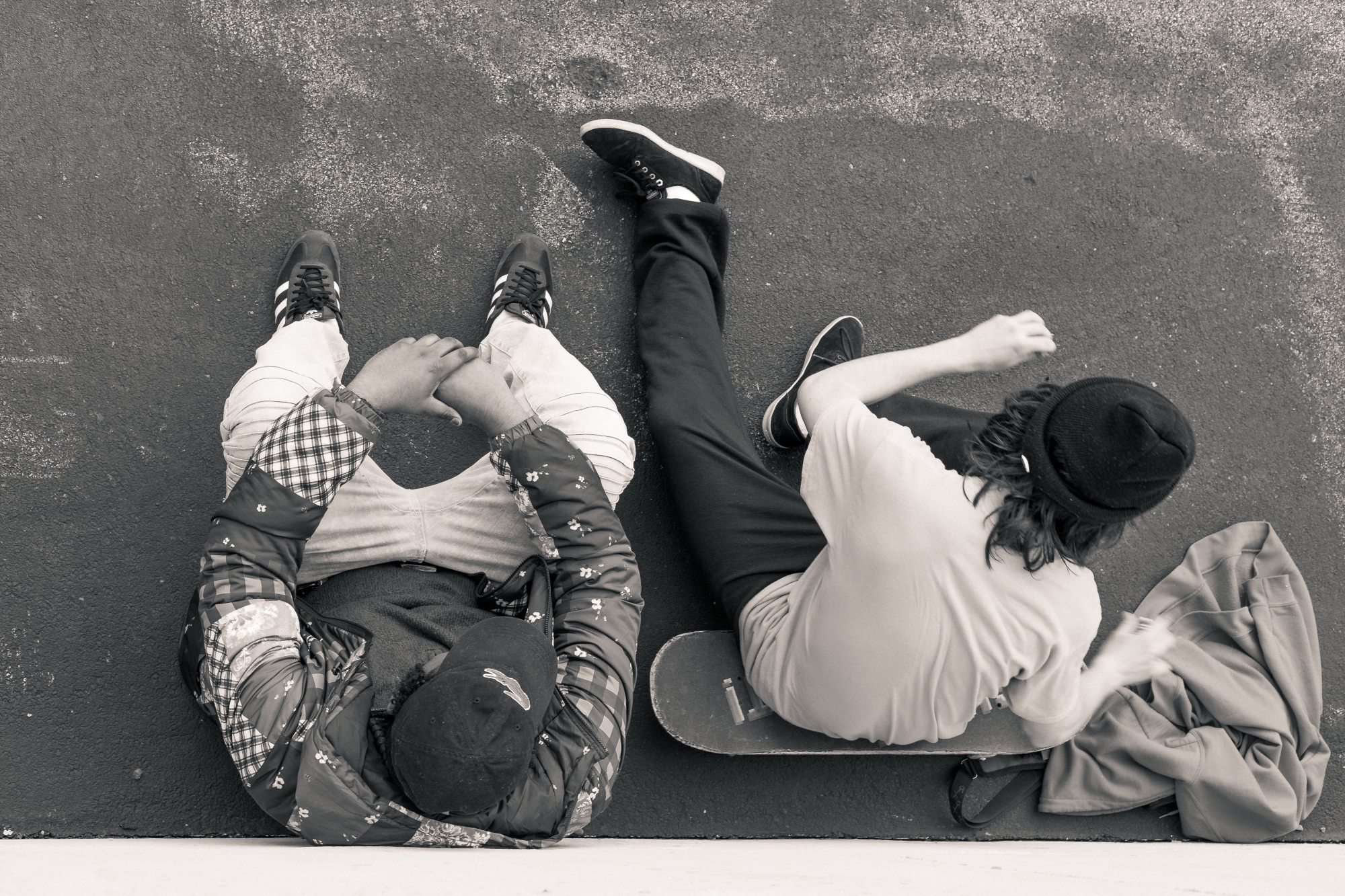 Two men on sitting, one on a skateboard