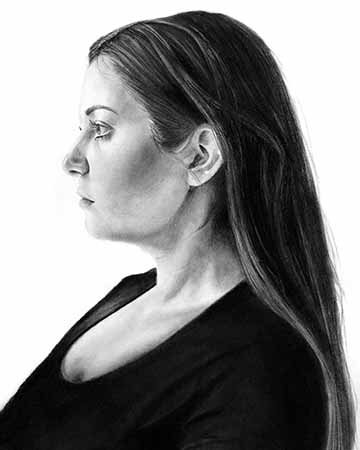 This charcoal drawing is a profile self-portrait of the female artist from the shoulders up. This is drawn in a traditional sense where features and volume are built up by arranging light are dark value amongst the figure.