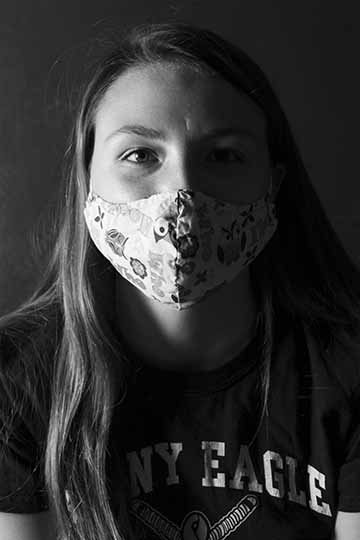 Black and white portrait with dramatic lighting of a woman with a mask on.
