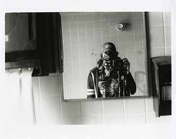Self portrait in an old abandoned bathroom mirror with soap dispenser and towel holder 