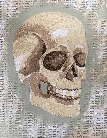 a fully embroidered skull on top of a background of continuous text stating “though i can’t recall your face, i still got love for you.” 