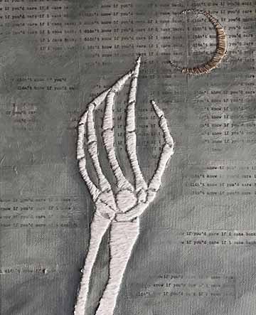 A white embroidered skeletal hand reaching for an embroidered crescent moon in the top right corner, on top of a hazy dark-painted background with the repeated text “I didn&#039;t know if you’d care if I came back.”