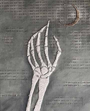 A white embroidered skeletal hand reaching for an embroidered crescent moon in the top right corner, on top of a hazy dark-painted background with the repeated text “I didn't know if you’d care if I came back.”