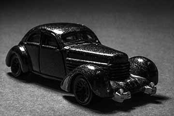 4 photographs of toy cars made to look like real cars. Each photo depicts a different car in an environment. Photo one depicts a car from the 1930’s in a dark, noir styled scene. Photo two depicts a rally car in the desert. Photo three depicts a suped up 1950’s truck. Photo four depicts a 1920’s car in a winter scene.