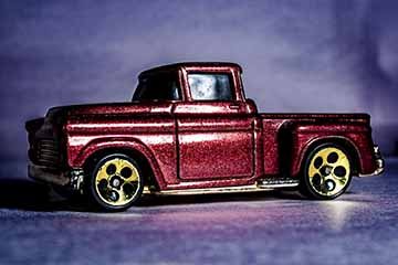 4 photographs of toy cars made to look like real cars. Each photo depicts a different car in an environment. Photo one depicts a car from the 1930’s in a dark, noir styled scene. Photo two depicts a rally car in the desert. Photo three depicts a suped up 1950’s truck. Photo four depicts a 1920’s car in a winter scene.