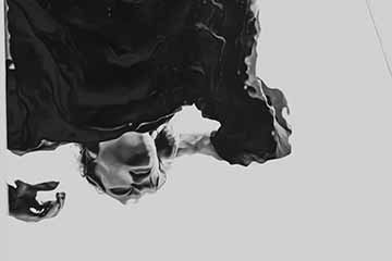 The photograph is a black and white medium shot self-portrait of the photographer, as a reflection in the mirror in Lake Ontario. 